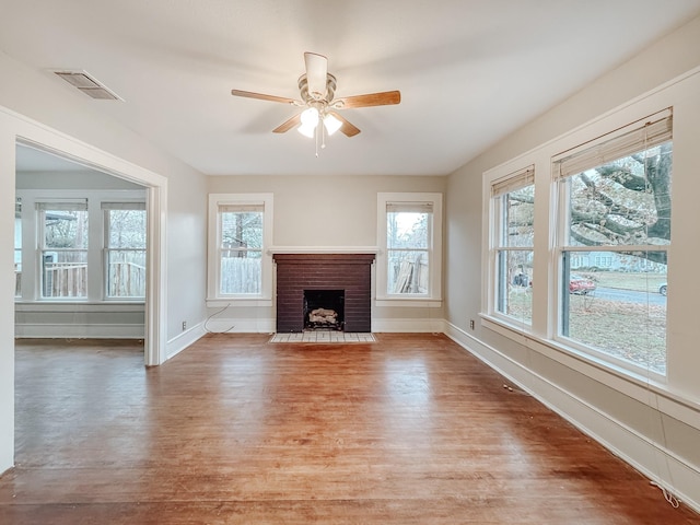 unfurnished living room with ceiling fan, a healthy amount of sunlight, light wood-type flooring, and a fireplace