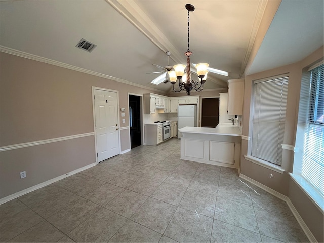 kitchen with vaulted ceiling, crown molding, stainless steel range oven, white cabinets, and white fridge