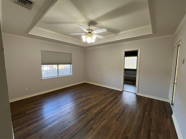 spare room with dark wood-type flooring, a raised ceiling, visible vents, and baseboards