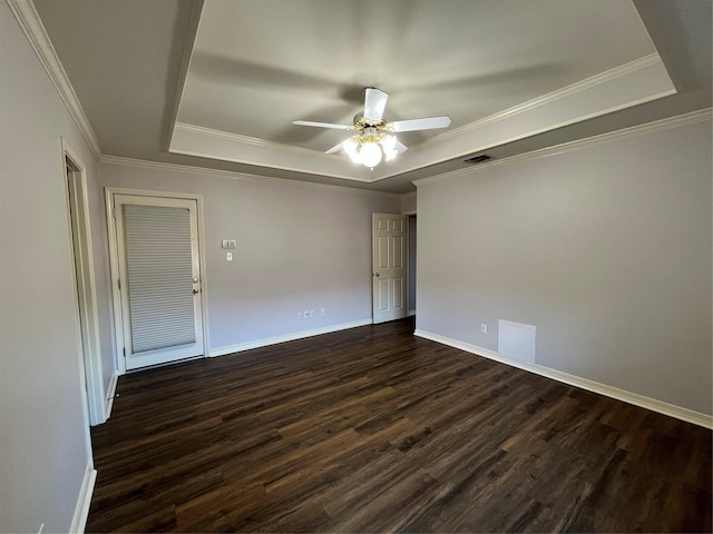 empty room featuring a ceiling fan, a tray ceiling, dark wood-style flooring, and visible vents