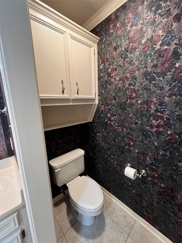 bathroom featuring baseboards, crown molding, toilet, and tile patterned floors