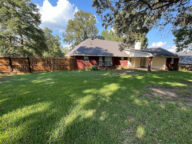 exterior space featuring a chimney, fence, and a lawn