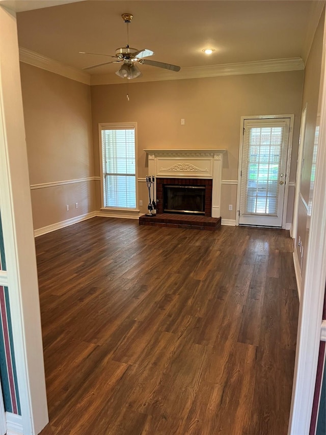 unfurnished living room featuring dark hardwood / wood-style floors, a brick fireplace, ceiling fan, and crown molding