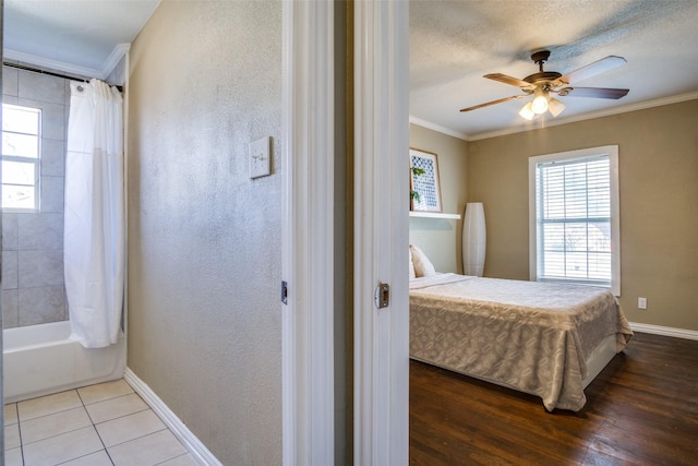 tiled bedroom featuring a textured ceiling, ceiling fan, and crown molding