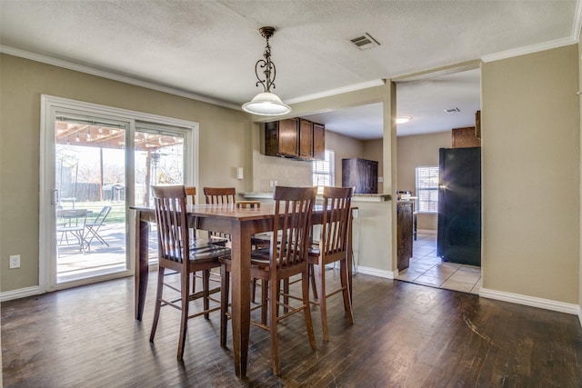 dining space with a textured ceiling, wood-type flooring, and ornamental molding