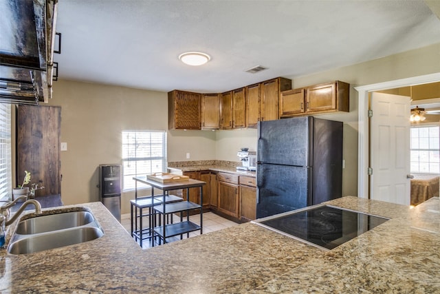 kitchen featuring a healthy amount of sunlight, sink, light tile patterned floors, and black appliances