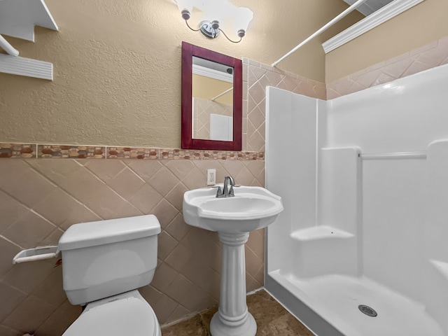 bathroom with a shower, toilet, tile walls, and ornamental molding