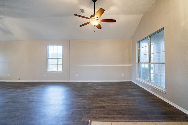 spare room with a textured ceiling, dark hardwood / wood-style floors, vaulted ceiling, and ceiling fan