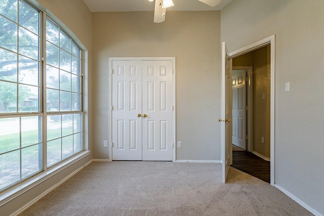 unfurnished bedroom featuring carpet flooring, ceiling fan, a closet, and multiple windows