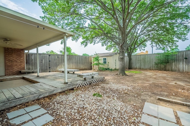 view of yard with an outbuilding, a deck, and ceiling fan