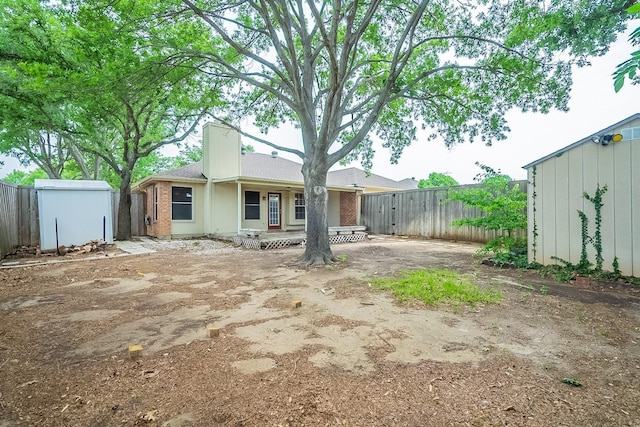 back of property featuring a storage shed and a deck