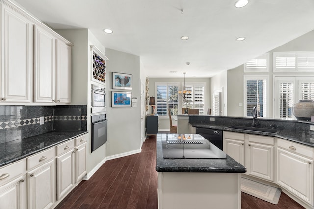 kitchen with a center island, black appliances, sink, decorative backsplash, and white cabinetry