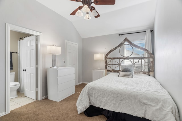 bedroom with ceiling fan, vaulted ceiling, light carpet, and ensuite bath