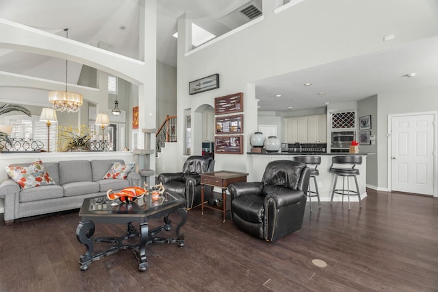 living room with dark wood-type flooring, a high ceiling, and an inviting chandelier