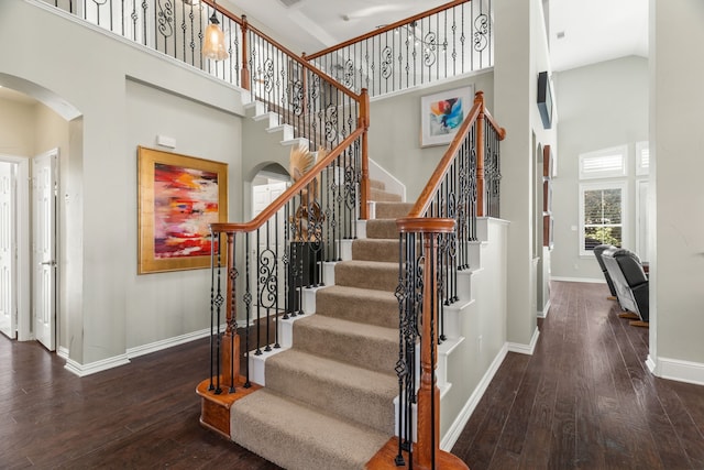 stairs with hardwood / wood-style floors and a towering ceiling