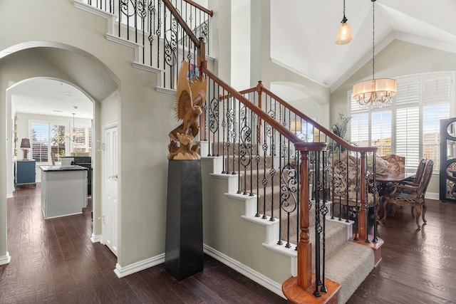 stairway with a chandelier, ornamental molding, hardwood / wood-style flooring, and lofted ceiling