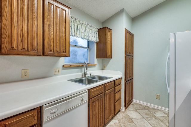 kitchen featuring a textured ceiling, white appliances, and sink