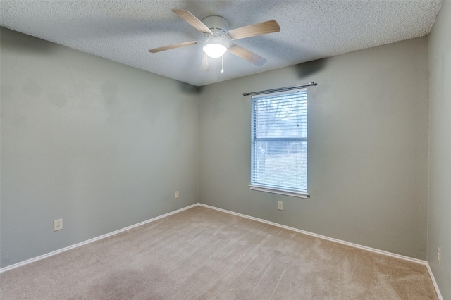 empty room featuring ceiling fan, light colored carpet, and a textured ceiling