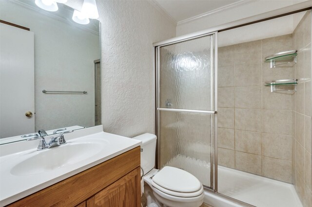 bathroom with toilet, vanity, crown molding, and a shower with shower door