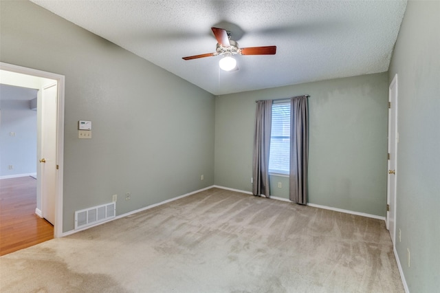 carpeted spare room featuring ceiling fan and a textured ceiling