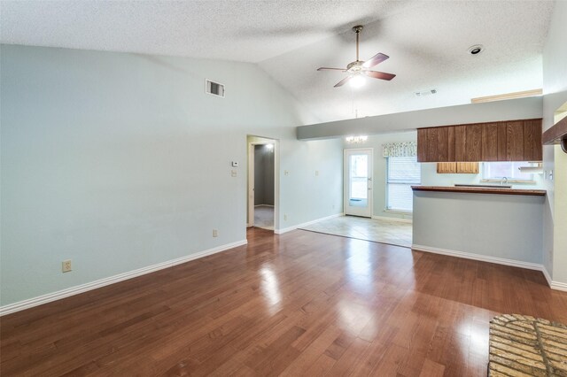 unfurnished living room with hardwood / wood-style flooring, ceiling fan, a textured ceiling, and vaulted ceiling