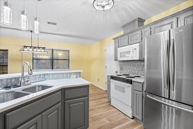 kitchen with white appliances, gray cabinets, hanging light fixtures, and sink