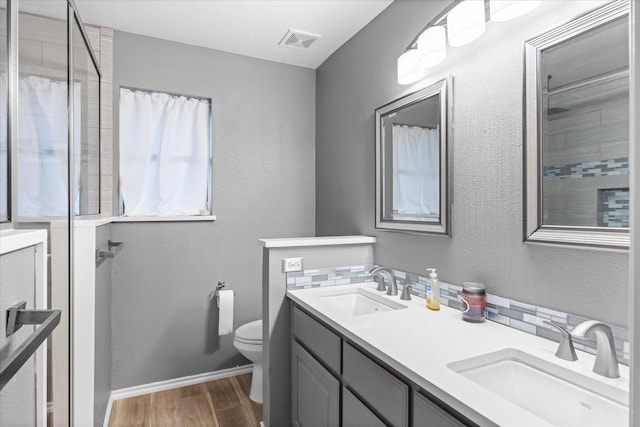 bathroom featuring wood-type flooring, vanity, toilet, and walk in shower