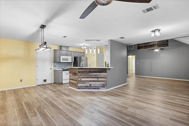 kitchen with stainless steel refrigerator, gray cabinetry, tasteful backsplash, stove, and light wood-type flooring