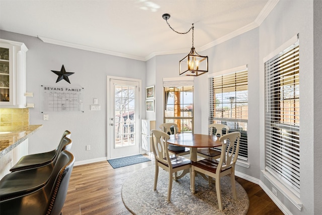 dining space with a chandelier, wood-type flooring, and ornamental molding