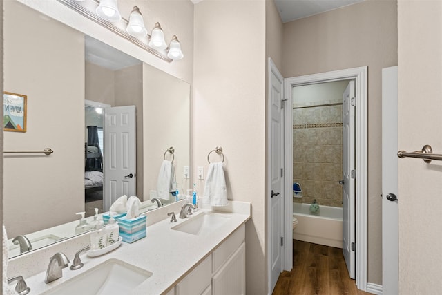 bathroom with vanity, wood-type flooring, and tiled shower / bath