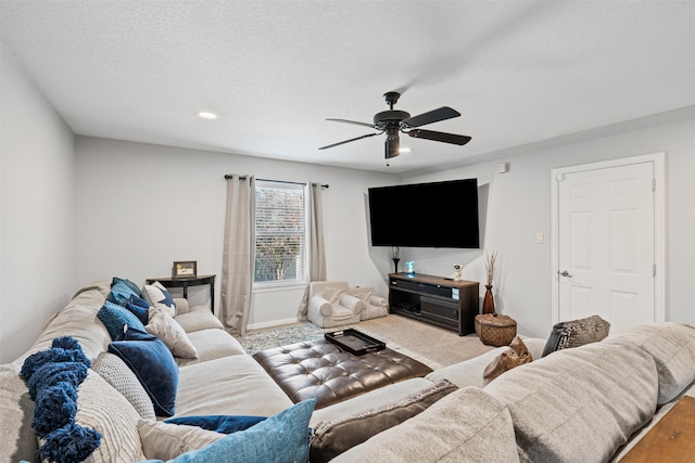 living room featuring ceiling fan, carpet floors, and a textured ceiling