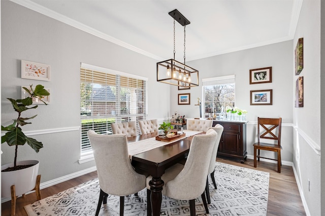 dining area featuring wood-type flooring, ornamental molding, and a notable chandelier