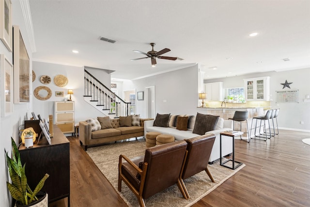 living room featuring hardwood / wood-style flooring, ceiling fan, sink, and crown molding