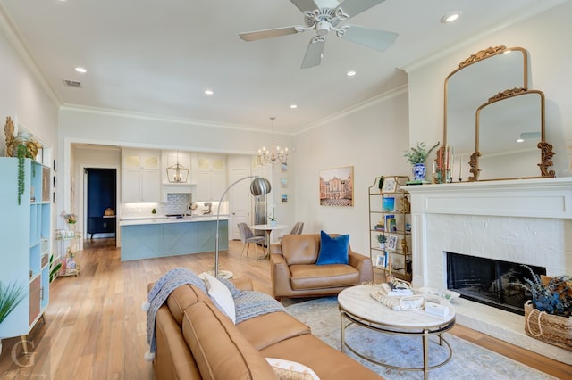 living room featuring crown molding, ceiling fan, a fireplace, and light hardwood / wood-style flooring