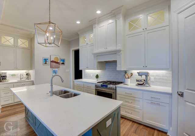 kitchen with white cabinetry, sink, a center island with sink, and high end stainless steel range