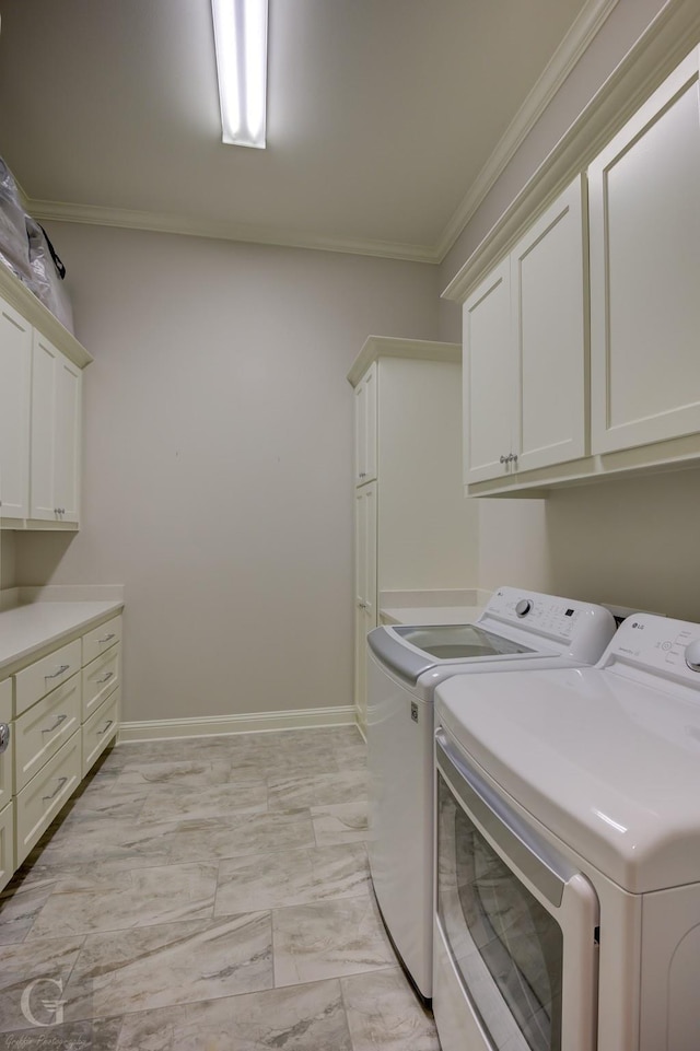 laundry room featuring cabinets, crown molding, and washing machine and clothes dryer