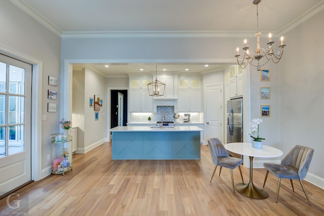 kitchen with pendant lighting, sink, a kitchen island with sink, and stainless steel refrigerator with ice dispenser