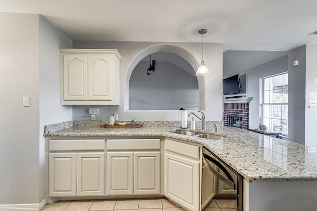 kitchen with light stone countertops, dishwasher, sink, a fireplace, and light tile patterned flooring