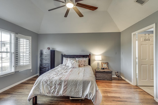 bedroom with ceiling fan, hardwood / wood-style floors, and vaulted ceiling