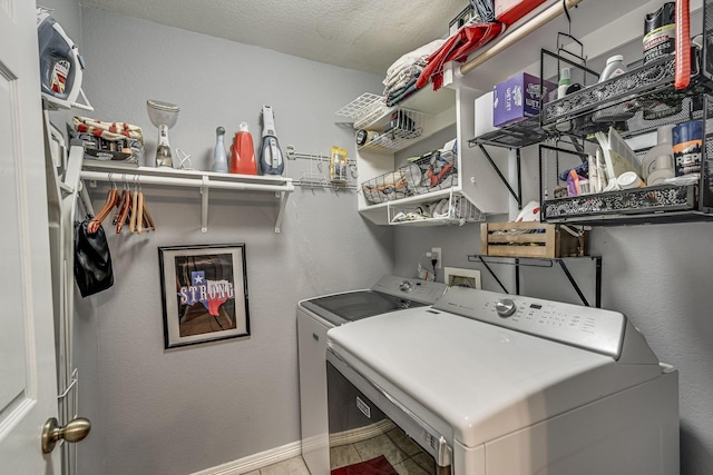 laundry area featuring washing machine and dryer, tile patterned flooring, and a textured ceiling