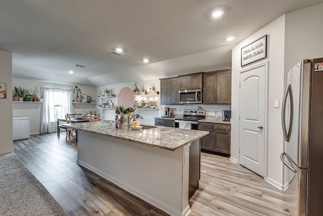 kitchen featuring sink, light stone countertops, a kitchen island, light hardwood / wood-style floors, and stainless steel appliances