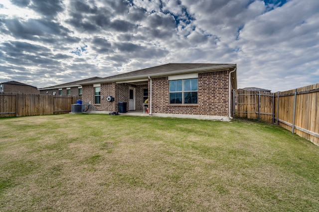 rear view of house with a lawn, central AC, and a patio