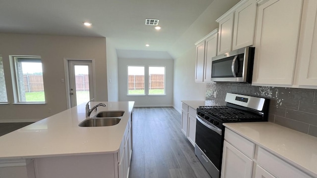 4224 Lucy Ln, Sherman, TX 75090 - kitchen with stainless steel appliances, a sink, wood finished floors, backsplash, and white cabinetry