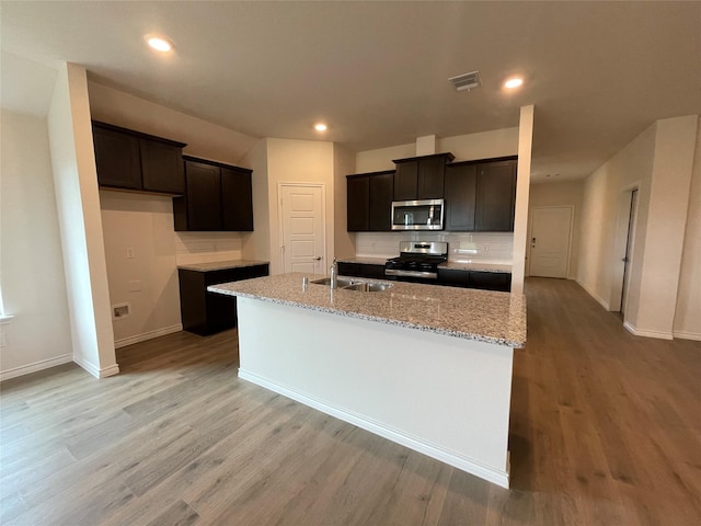 4219 Sky Dr, Sherman, TX 75090 - kitchen with appliances with stainless steel finishes, baseboards, light wood finished floors, a kitchen island with sink, and recessed lighting