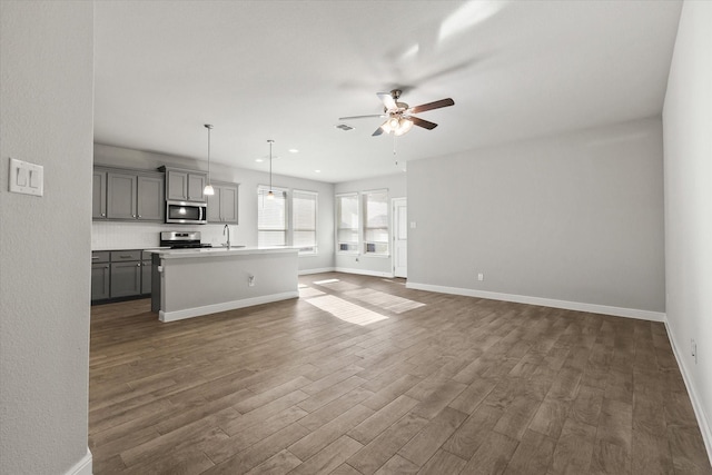 unfurnished living room featuring ceiling fan, sink, and dark wood-type flooring