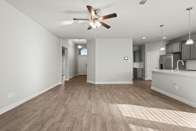 unfurnished living room featuring ceiling fan, light wood-type flooring, and sink