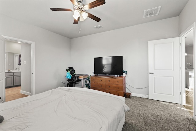 bedroom with connected bathroom, light colored carpet, ceiling fan, and sink