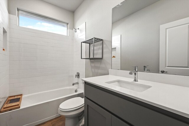 full bathroom with hardwood / wood-style flooring, tiled shower / bath combo, toilet, and vanity