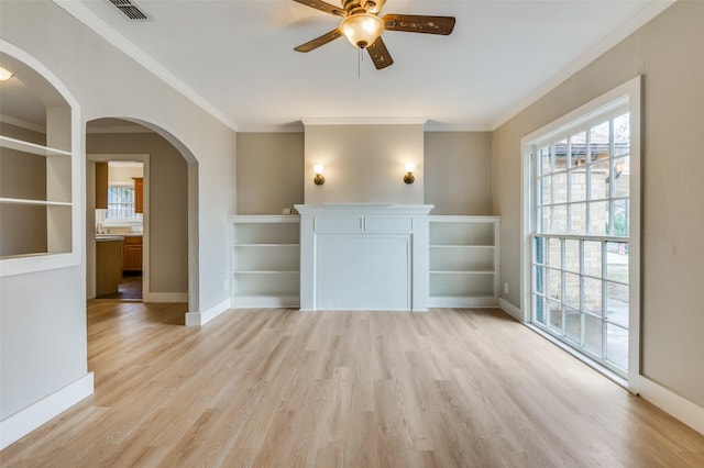 unfurnished living room featuring ceiling fan, light wood-type flooring, and ornamental molding