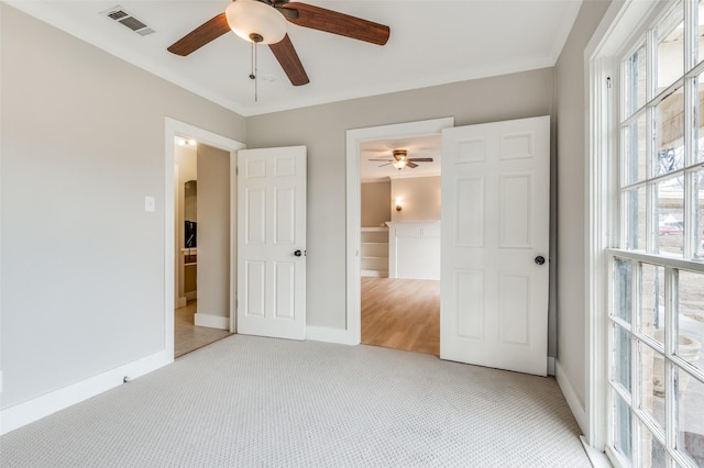 unfurnished bedroom with ceiling fan, light colored carpet, crown molding, and connected bathroom